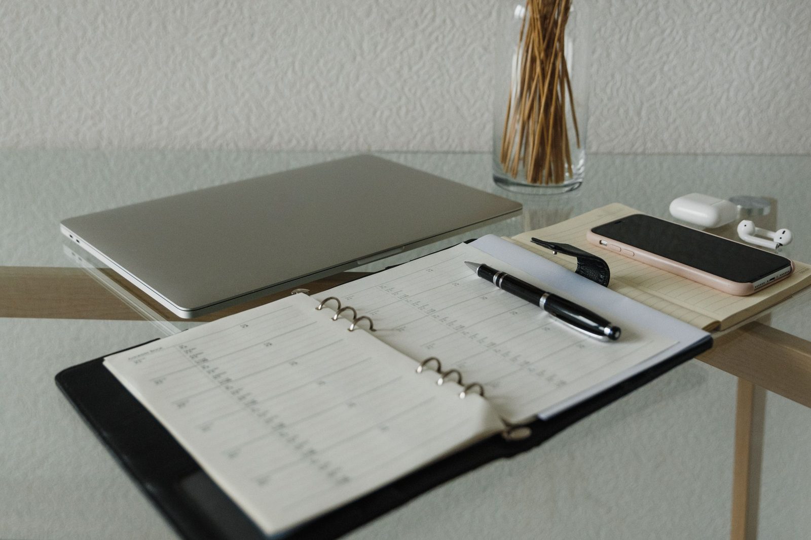 Een bureau met een laptop, een opengeslagen agenda, een pen en een telefoon