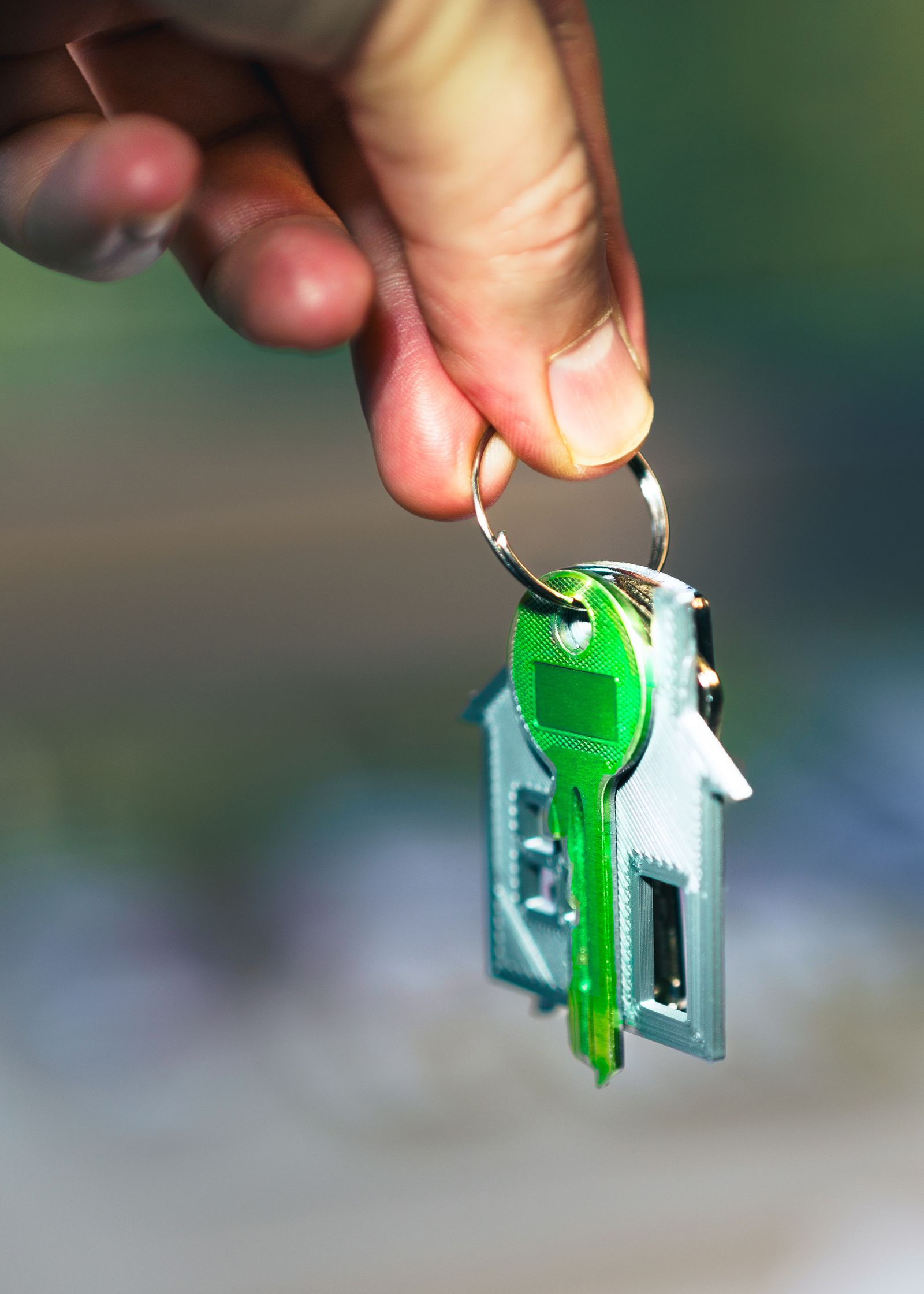 Hand overhandigt een huissleutel met huisvormige sleutelhanger, symbool voor SEO voor makelaars