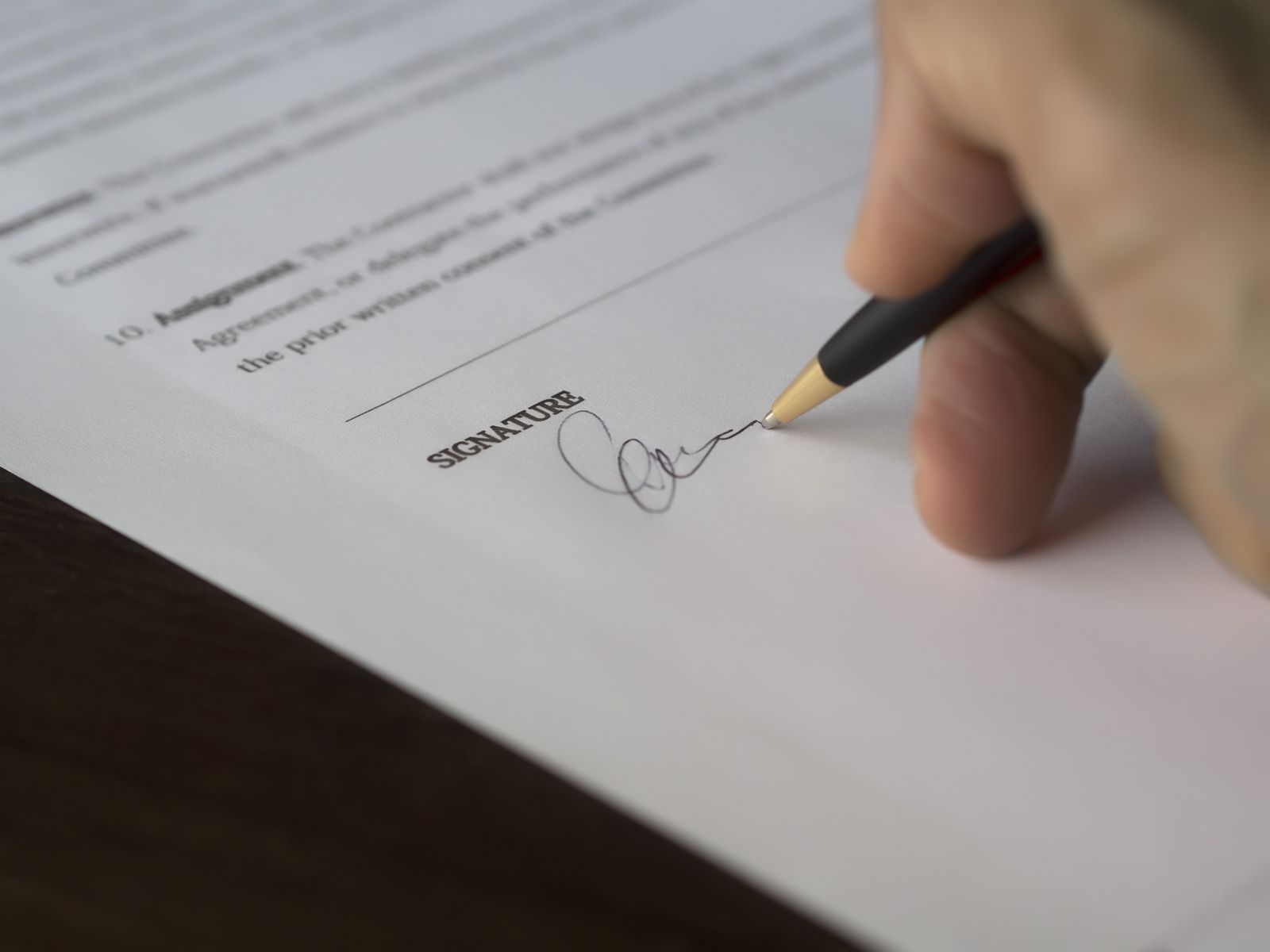Close-up van een hand die een akte ondertekent, symbool voor SEO voor notarissen